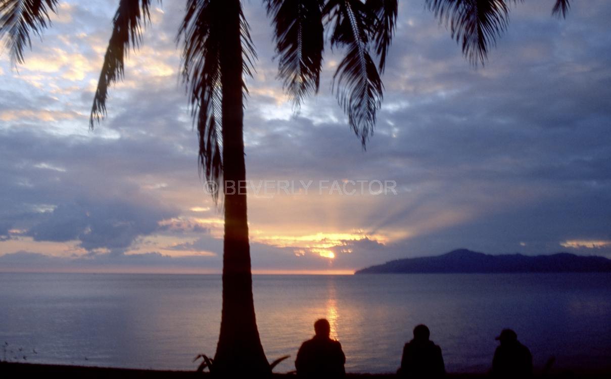 Island Sunsets;Papua New Guinea;sky;sillouettes;sunset;water;red;colorful;yellow;ocean;palm trees;people